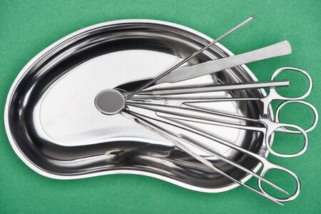 top view of set with stainless dental tools in plate isolated on green