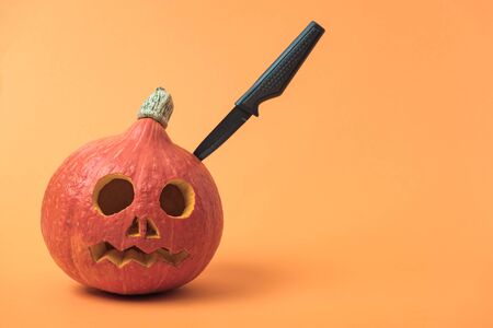 Halloween pumpkin with knife on orange backgroundの写真素材