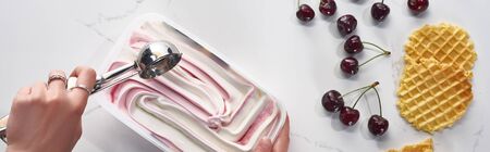 cropped view of woman with delicious ice cream and_spoon near waffles and cherries on marble grey...