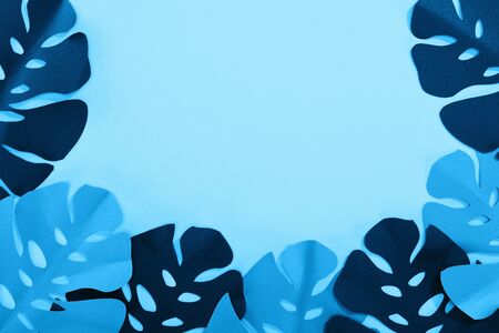 top view of paper cut tropical leaves on blue minimalistic background with copy spaceの写真素材