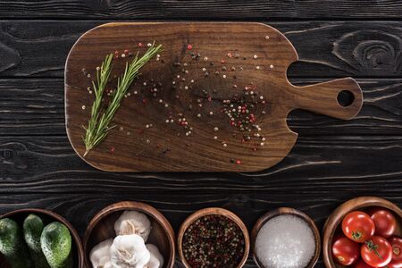 top view of cutting board, cherry tomatoes, greenery, salt, garlics, cucumbers and spices