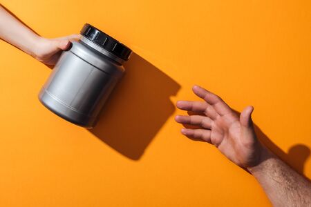 cropped view of woman holding grey jar near man on yellowの写真素材