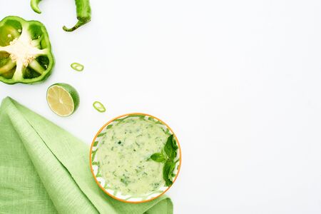 top view of delicious creamy green vegetable soup served with napkin isolated on whiteの写真素材