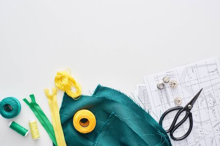 top view of zippers, scissors, thimbles, threads, knitting yarn balls, fabric and sewing patterns on white backgroundの写真素材