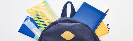 Panoramic shot of blue school bag with notepads and pencil case isolated on white