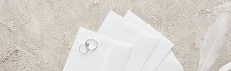 panoramic shot of silver rings on white envelopes on textured surfaceの写真素材