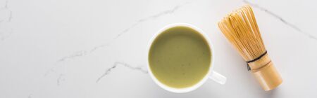 top view of green matcha tea with whisk on white table
