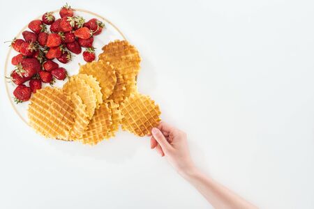 cropped view of woman holding waffle near plate on whiteの写真素材