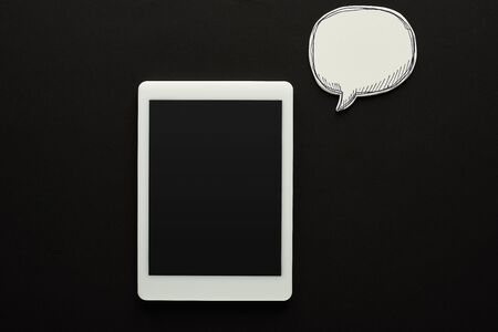 top view of digital tablet with blank screen on black background near empty white speech bubble, cyberbullying conceptの写真素材