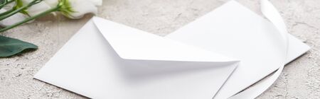 panoramic shot of envelope near eustoma flowers and white ribbon on grey textured surfaceの写真素材