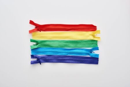 top view of bright and colorful zippers on white background