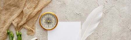panoramic shot of quill pen on piece of paper near beige sackcloth and golden compass on grey textured surfaceの写真素材