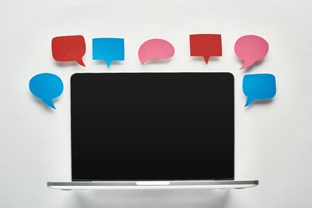 laptop with blank screen on white background near empty colorful speech bubbles, cyberbullying conceptの写真素材