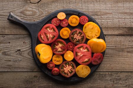 top view of pizza pan with sliced tomatoes on wooden tableの写真素材
