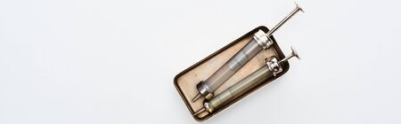 top view of aged syringes in vintage box on white background with copy space, panoramic shot
