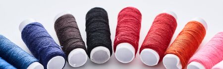 panoramic shot of bright and colorful threads on white background