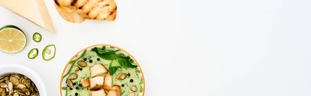 top view of delicious creamy green vegetable soup with sprouts, grilled croutons and pumpkin seeds isolated on white, panoramic shotの写真素材