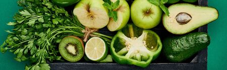 panoramic shot of apples, avocados, pepper, kiwi, greenery, lime in wooden boxの写真素材