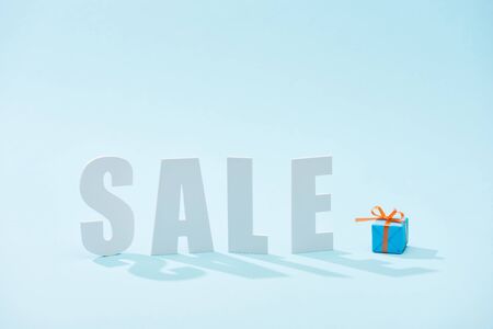 white sale lettering and festive gift box on blue backgroundの写真素材