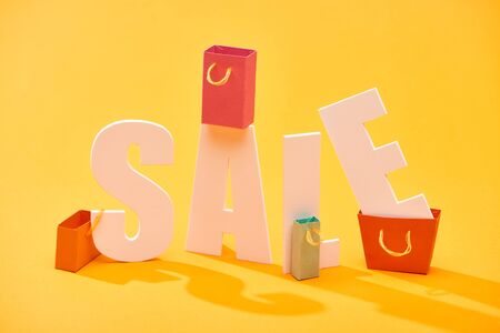 white sale lettering with shopping bags on bright orange backgroundの写真素材