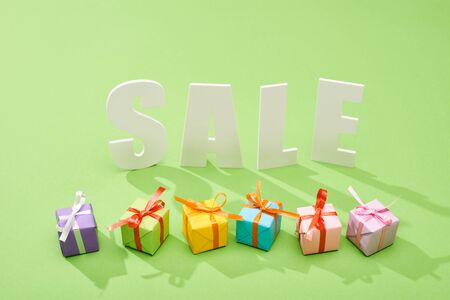 white sale lettering near decorative festive gift boxes on green backgroundの写真素材
