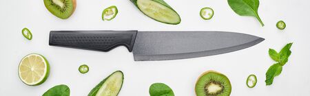 panoramic shot of knife, fresh cucumbers, kiwi, lime, peppers and greenery