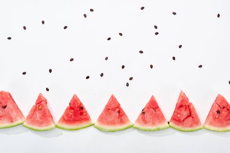 flat lay with delicious juicy watermelon slices and scattered seeds on white background