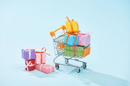festive wrapped gifts in shopping cart on blue backgroundの写真素材