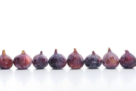 ripe whole delicious figs in row on white background