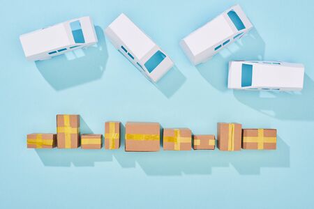 top view of closed cardboard boxes near van on blue background with copy spaceの写真素材
