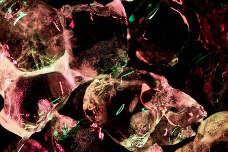 close up view of transparent ice cubes with red and green illumination isolated on black