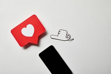 smartphone with pointing and like sign card on white surfaceの写真素材