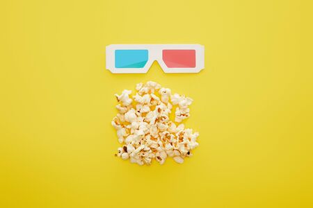 top view of delicious popcorn and 3d glasses on yellow backgroundの写真素材