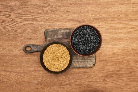 top view of bowls with beans and grains on wooden cutting boardの写真素材