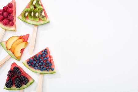 top view of tasty watermelon on sticks with seasonal berries and fruits on white background with...