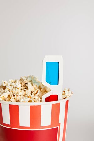 tasty fresh popcorn in bucket with 3d glasses isolated on greyの写真素材