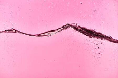 wavy clear fresh water on pink background with drops and bubblesの写真素材