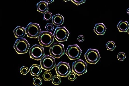 close up view of scattered metal nuts isolated on black
