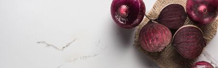 panoramic shot of beetroots and red onions on marble table with hessianの写真素材