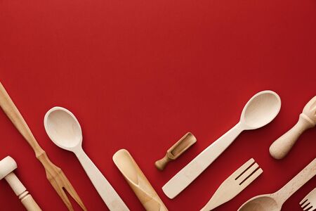 top view of woden spoons, forks, chopsticks and kitchenware on red background with copy spaceの写真素材