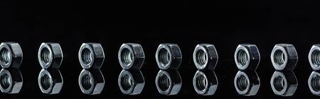panoramic shot of metallic nuts row isolated on black