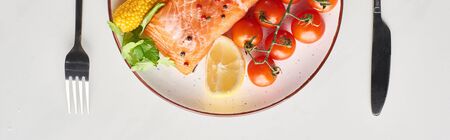 top view of raw salmon steak with  vegetables on plate near cutlery on marble table, panoramic shotの写真素材
