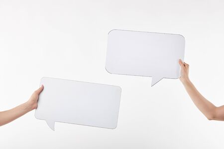 cropped view of two women with speech bubbles in hands isolated on whiteの写真素材