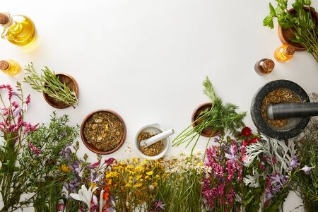top view of mortars and pestles with herbal blends near flowers on white backgroundの写真素材