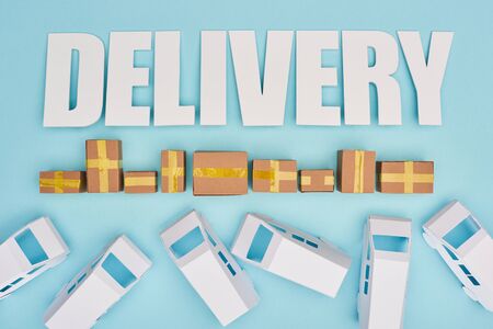 delivery inscription near closed cardboard boxes and mini van on blue backgroundの写真素材