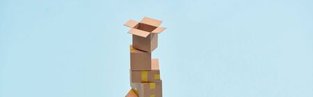 panoramic shot of tower of miniature boxes on blue background with copy space