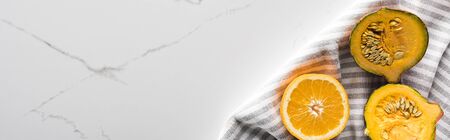 panoramic shot of striped towel with orange and pumpkin on marble surface