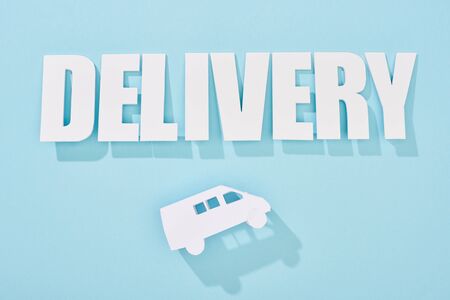 white delivery inscription with shadow above mini van on blue backgroundの写真素材