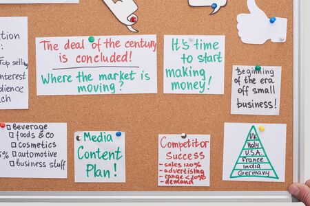 top view of cards with work plan notes pinned on office cork boardの写真素材