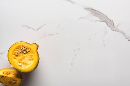 top view of raw pumpkin half and quarter on marble surfaceの写真素材